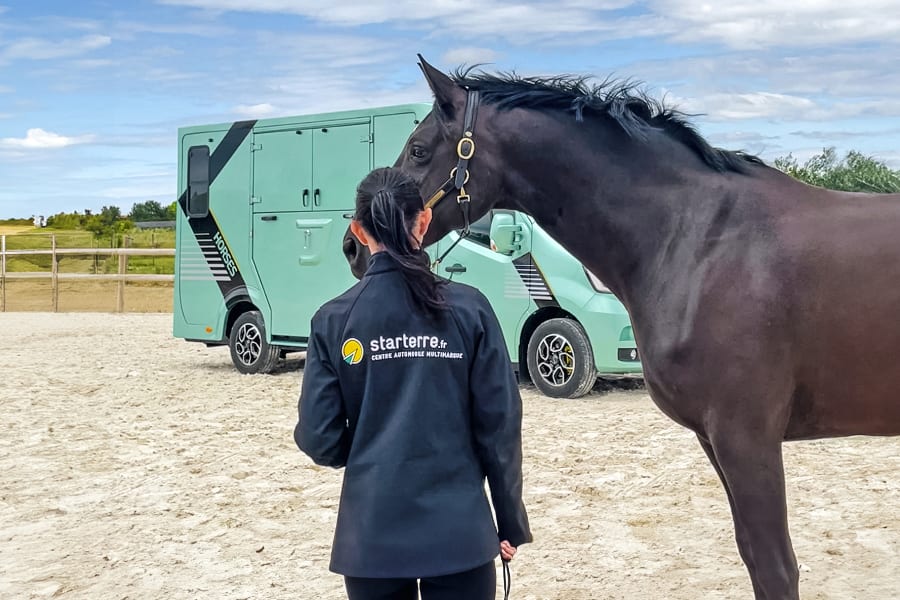 une éleveuse et son cheval devant un camion chevaux